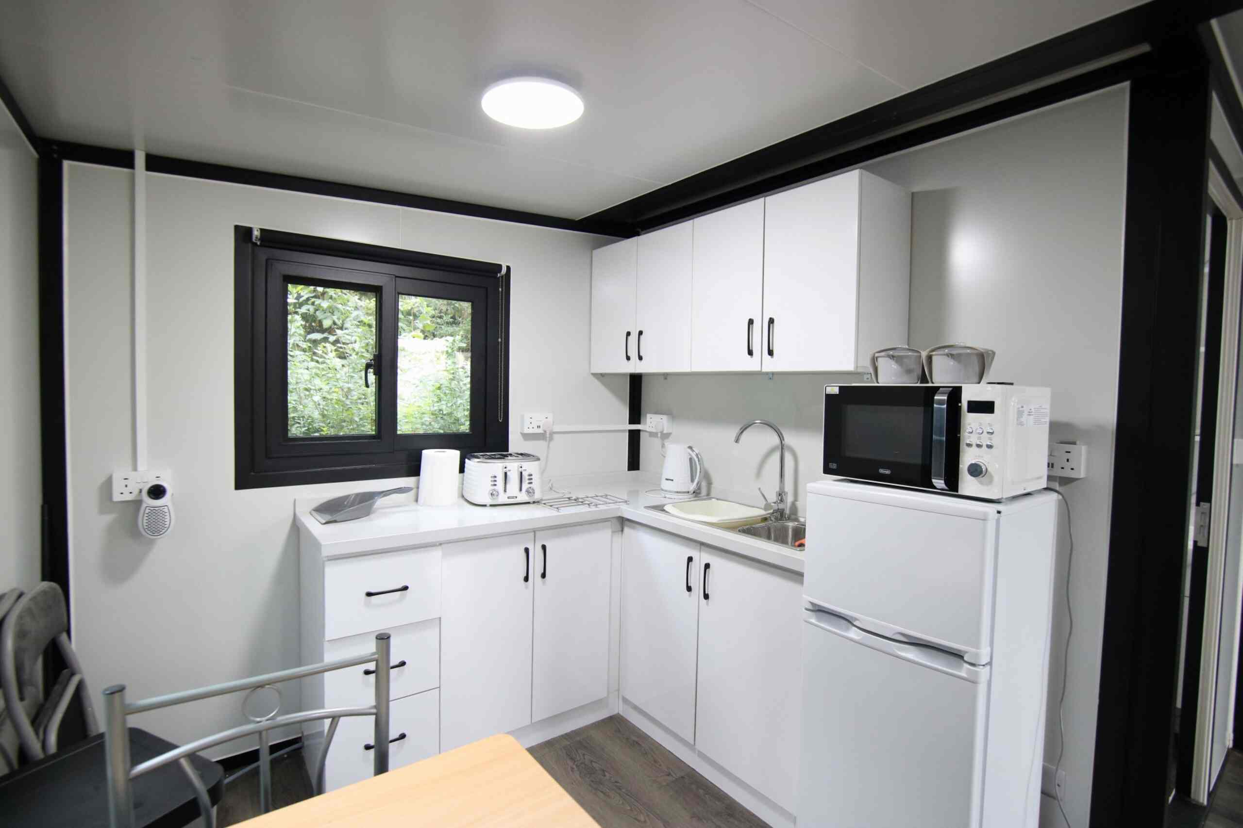 Compact fitted kitchen with fridge, microwave, kettle, toaster and sink