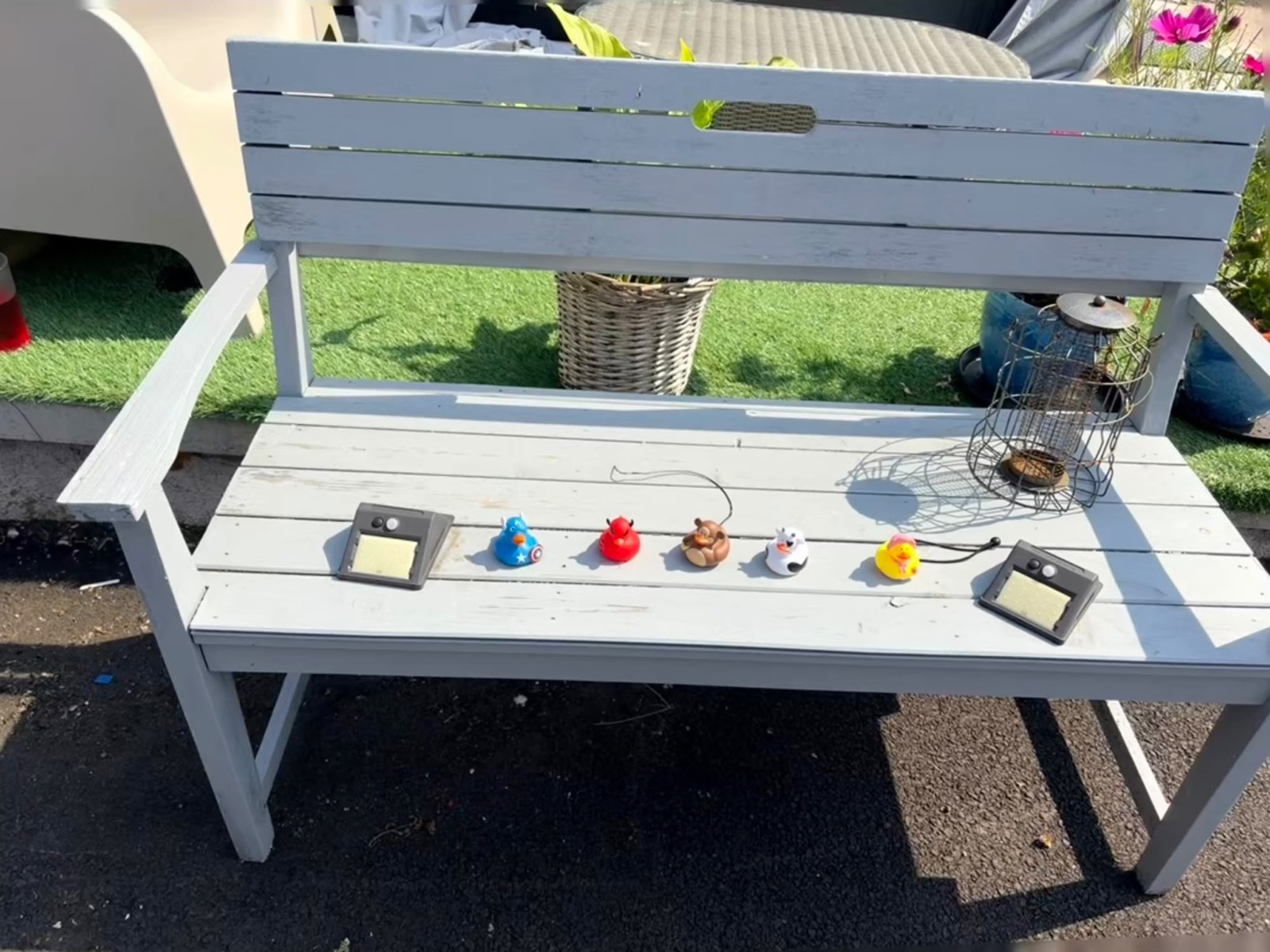 Painted garden bench with a row of rubber ducks and solar lights