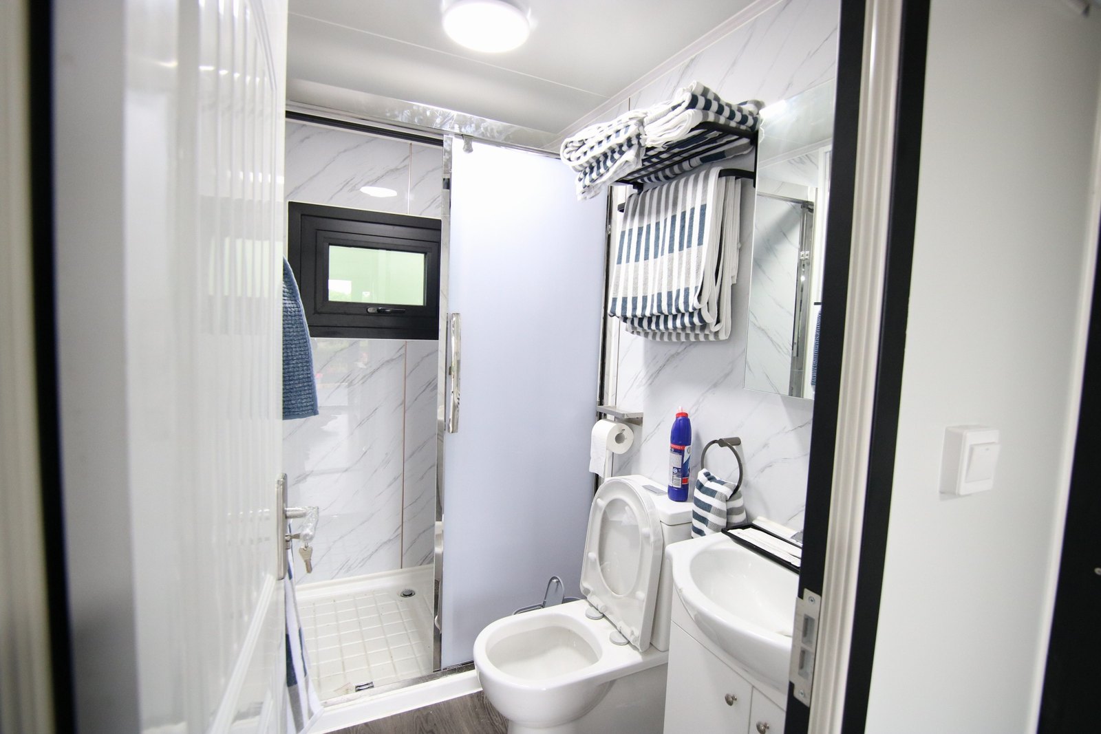 Shower room with a large shower, basin and stacked towels