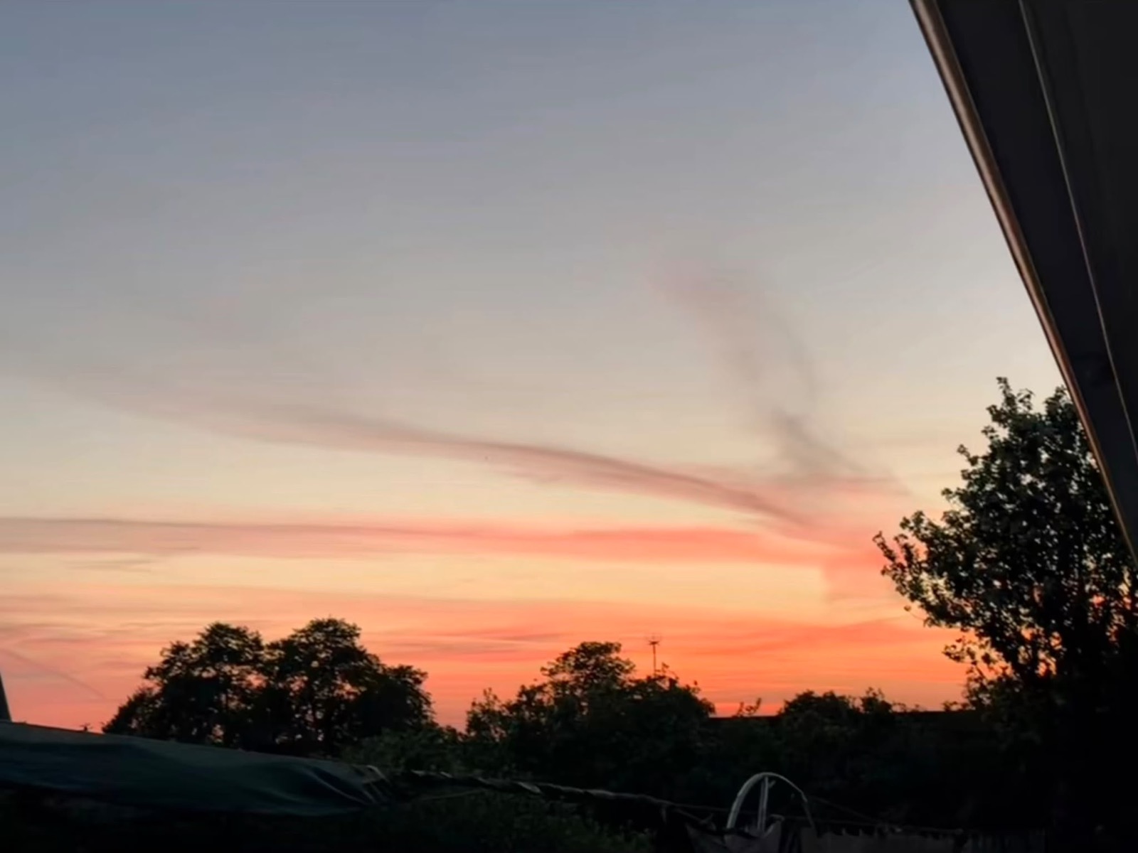 Orange and pink sunset over treetops, seen from the cabin